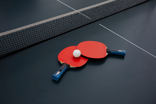 Red rackets and ping pong ball for table tennis.